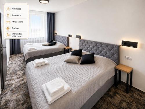 a hotel room with two beds with towels on them at Olympland Hotel in Trutnov