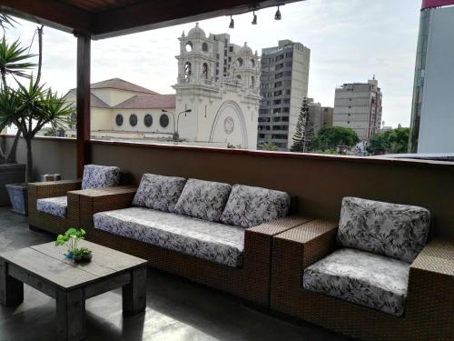 un sofá y 2 sillas en un balcón con un edificio en Lima Wasi Hotel Miraflores, en Lima