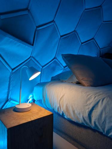 a bedroom with a bed with a blue wall at Dôme Renard by Out & Lodge in Couvin