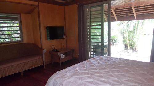 a bedroom with a bed and a tv and a window at Villa ManaOra in Taravao