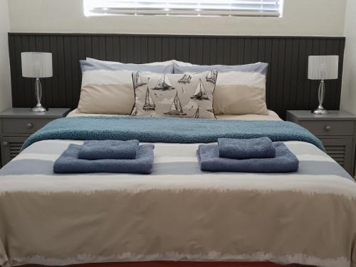 a large bed with two blue pillows on it at The Goose Nest in Struisbaai