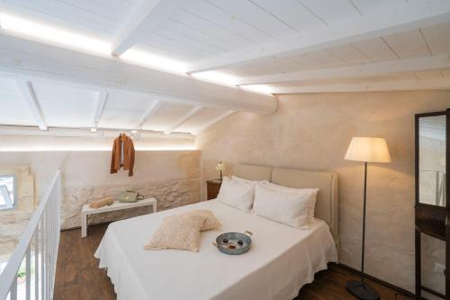 a bedroom with a white bed and a lamp at HISTORIA - Dimore in Corte in Borgagne