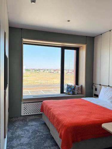 a bedroom with a large window and a red bed at Keruen inn Karaganda in Karagandy