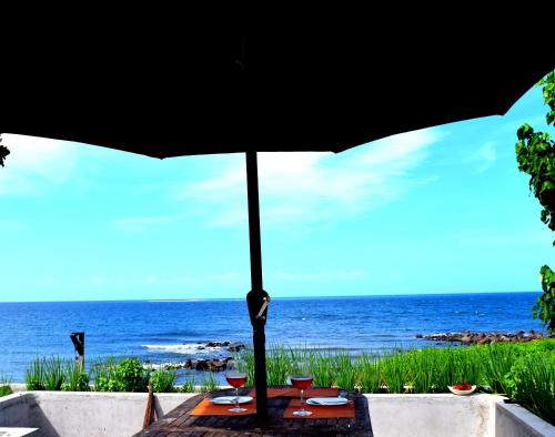 a table with a black umbrella and the ocean at Guerrera Rice Paddy Villas in Mambajao