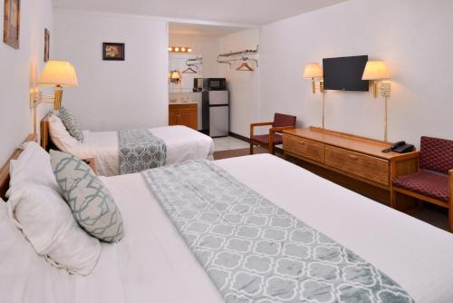a hotel room with two beds and a television at Red Carpet Inn Battleboro in Battleboro