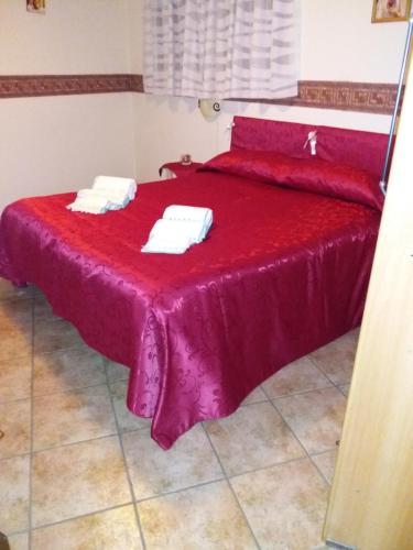 a red bed with two towels on top of it at La Casa di Petra in Modica