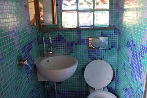 a blue tiled bathroom with a sink and a toilet at Romantic Studio Apartment Near Park in Rome