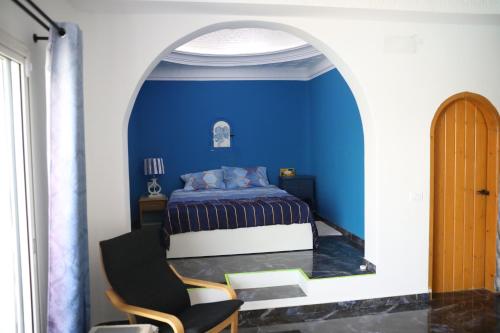 a blue bedroom with a bed and a chair at Dar Mimouna Djerba in Tianest