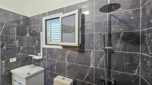 a bathroom with a shower and a window and a toilet at Guesthouse - VILA QETESIA in Përmet