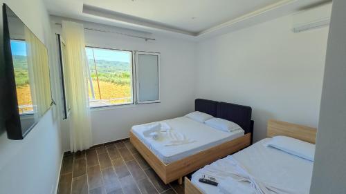 two beds in a room with two windows at Guesthouse - VILA QETESIA in Përmet