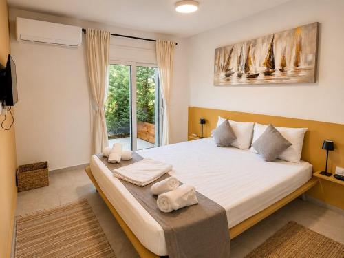 a bedroom with a large bed and a window at Villa Maria Apartments by BookVillaEU in Nea Kallikrateia