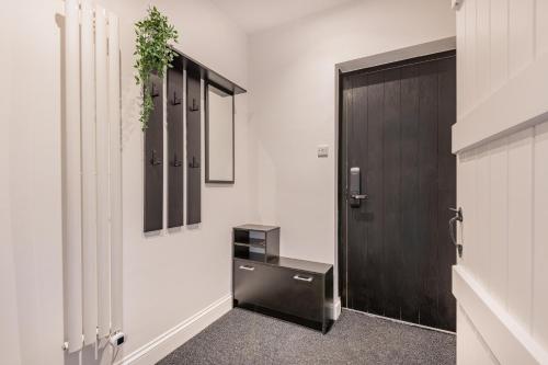 a hallway with a black door and a black desk at Southend Cottage By Birch Stays in Penrith