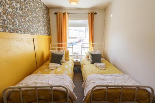 two beds in a small room with a window at Southend Cottage By Birch Stays in Penrith