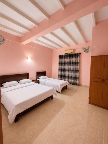 two beds in a room with pink walls at Prabha Garden Boutique Villa in Anuradhapura