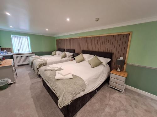 two beds in a bedroom with green walls at Moorside Hotel and Cafe in Stoupe Brow
