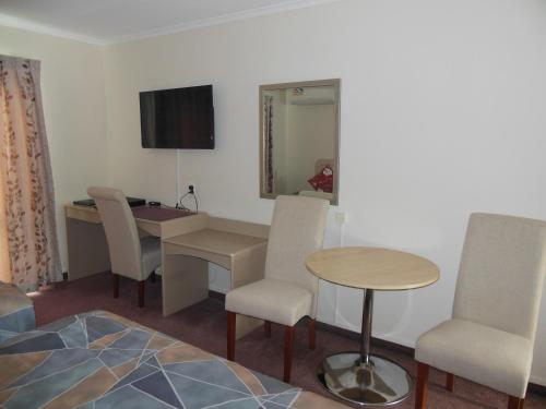 a room with a table and chairs and a desk at ASURE Camelot Arms Motor Lodge in Auckland