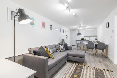 a living room with a gray couch and a kitchen at Charming Two Bed - Two Bath Apt (25KM) in Headingley