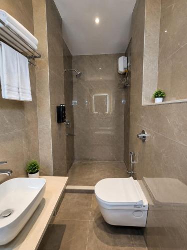 a bathroom with a toilet and a sink and a shower at The Kingsway Suites in Nagpur