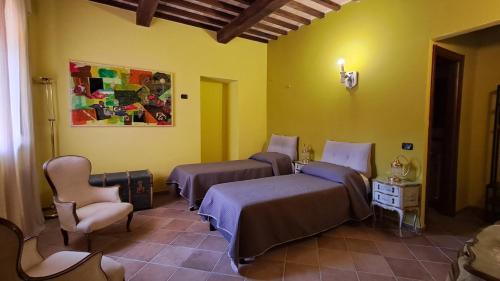a bedroom with two beds and chairs in a room at Bio Agriturismo Valle dei Calanchi in Castiglione in Teverina