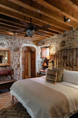 a bedroom with a bed in a stone wall at Hacienda Las Amantes in San Miguel de Allende