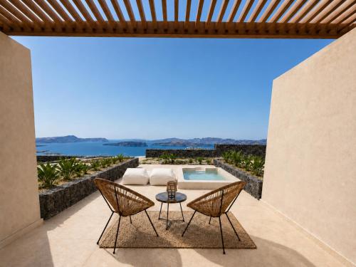 a patio with a table and chairs and a swimming pool at Vespera Private Luxury Suites in Santorini