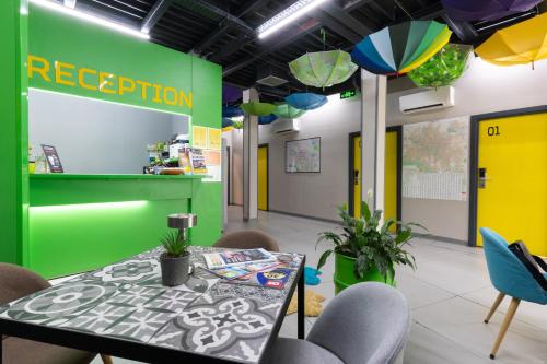 a table and chairs in a room with a green wall at Green Cube Capsule Hostel in Sofia