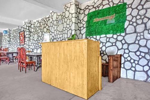 a room with a table and chairs and a stone wall at Collection O near Museum Pusaka Karo formerly 3 Berastagi in Berastagi