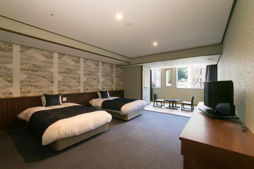 a hotel room with two beds and a television at Suimeikan in Gero
