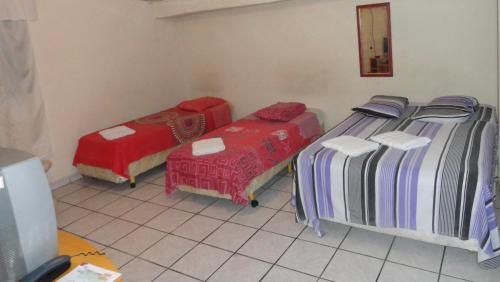 a room with two beds and a chair and a mirror at Hotel Capriccio Mauá in Mauá