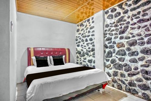 a bedroom with a large stone wall and a bed at Collection O near Museum Pusaka Karo formerly 3 Berastagi in Berastagi
