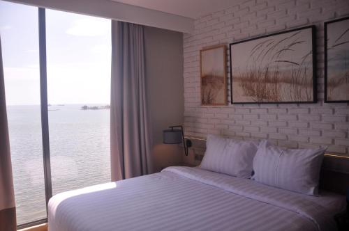 a hotel room with a bed and a large window at Expressia Hotel Makassar in Makassar
