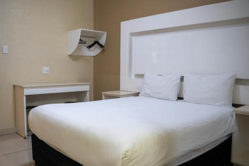 a bedroom with a large bed with white sheets at Palace Lodge Morningside in Durban