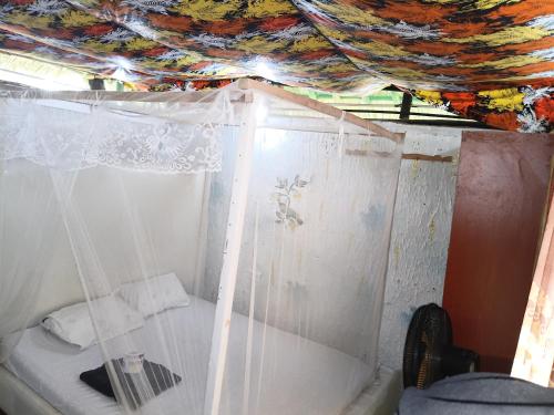a small room with a bed with a curtain at Baba Lao Beach Hostel in Malindi