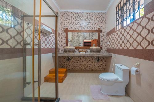 a bathroom with a shower and a toilet and a sink at Tan-Swiss Inn in Mikumi