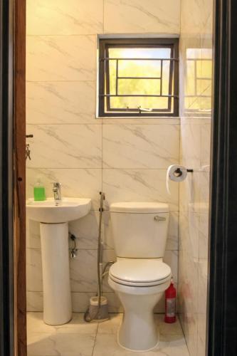 a bathroom with a toilet and a sink at Peaceful Home Self-catering Solar Backed Apartment in Lusaka