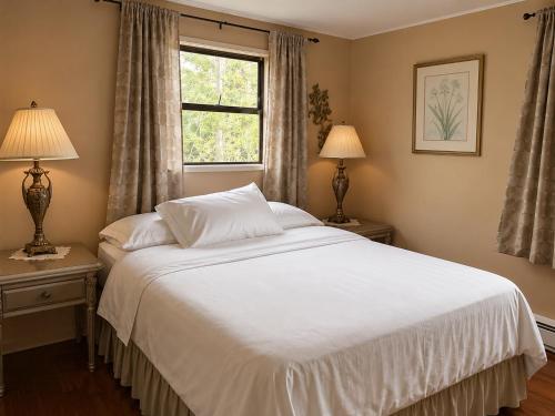 a bedroom with a white bed and a window at The Country Barn in Port Alberni