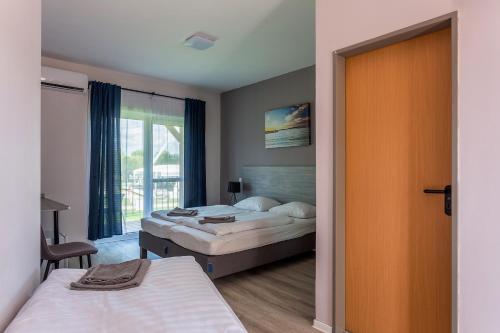 a bedroom with two beds and a sliding door at Holiday Hotel Siófok in Siófok