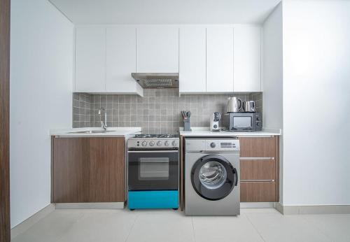 a kitchen with a stove and a washing machine at Stunning Oceanfront Studio Stay - Blue Bay Walk Pool & Gym in Sharjah
