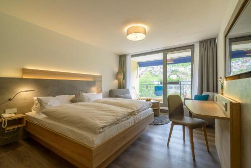 a hotel room with a bed and a desk and a desk at Biosphärenhotel Graf Eberhard bei der Therme Bad Urach in Bad Urach