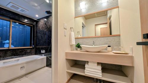 a bathroom with a sink and a tub and a mirror at Dream Stays HIKARI in Osaka
