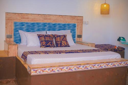 a bedroom with a large bed with a blue headboard at Bahari Studio Apartment in Bwejuu