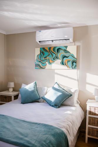 a bedroom with a white bed with blue pillows at Jakaranda Cabin - Self Catering Apartment in Secunda