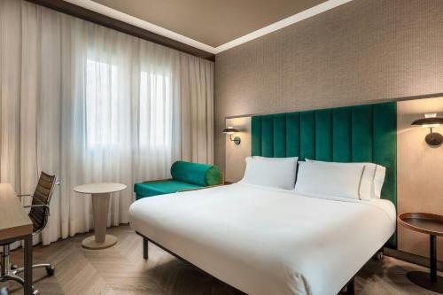 a hotel room with a large bed and a green headboard at AC Hotel Bologna by Marriott in Bologna