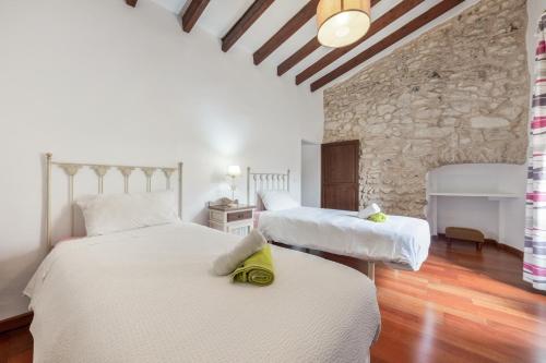 two beds in a room with a stone wall at Can Vallori in Sencelles