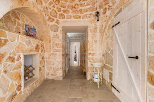 a hallway with a stone wall and a door at Trullo Sobba Llera by BarbarHouse in San Michele Salentino