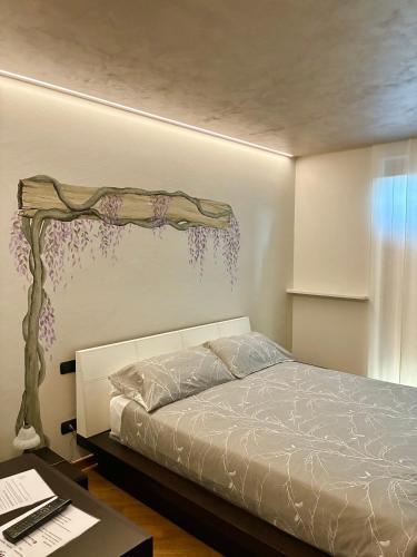 a bedroom with a bed with a branch on the wall at Antea Nuevo Sol Rooms and Breakfast in San Pellegrino Terme
