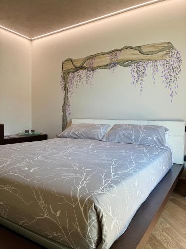 a bedroom with a bed with a branch on the wall at Antea Nuevo Sol Rooms and Breakfast in San Pellegrino Terme