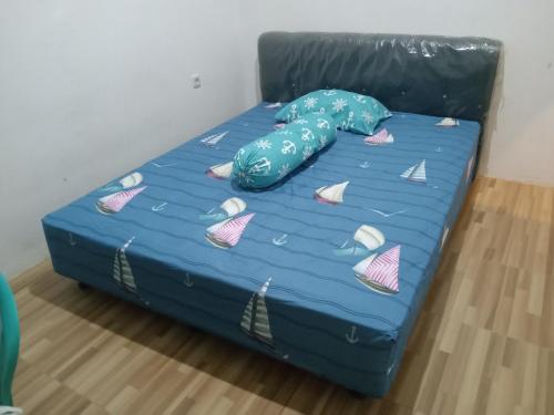 a bed with a blue sheet and a pillow on it at Kost Eka Gorontalo in Telaga