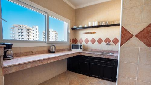 a kitchen with a sink and a window and a microwave at Intouriste Hotel & Suites in Agadir