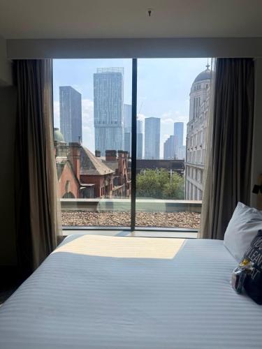 a bedroom with a large window with a view of the city at Moxy Manchester City Centre in Manchester